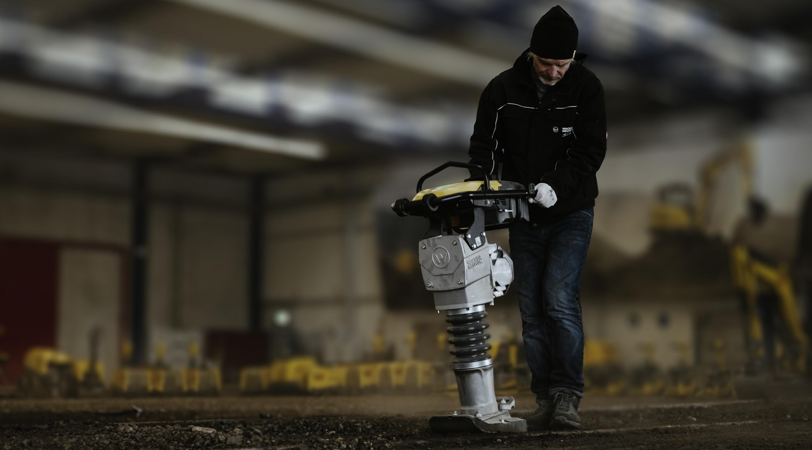 Pracovník obsluhující pěchovací stroj pro zhutňování zeminy ve výcvikovém prostředí pro vnitřní stavební práce