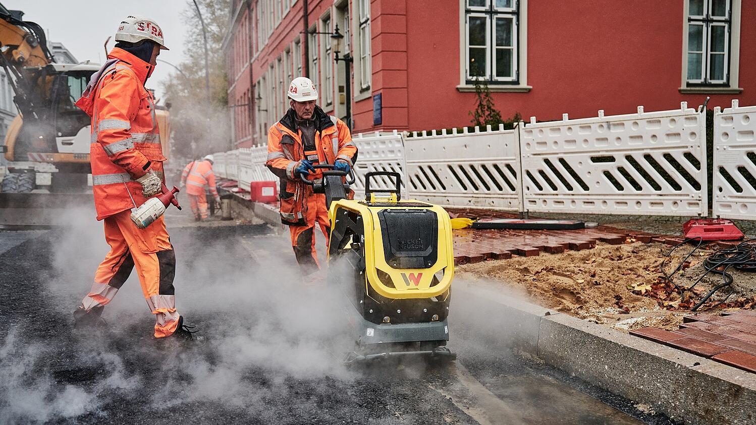 Stavební dělníci pokládají dlažbu pomocí stroje DPU62