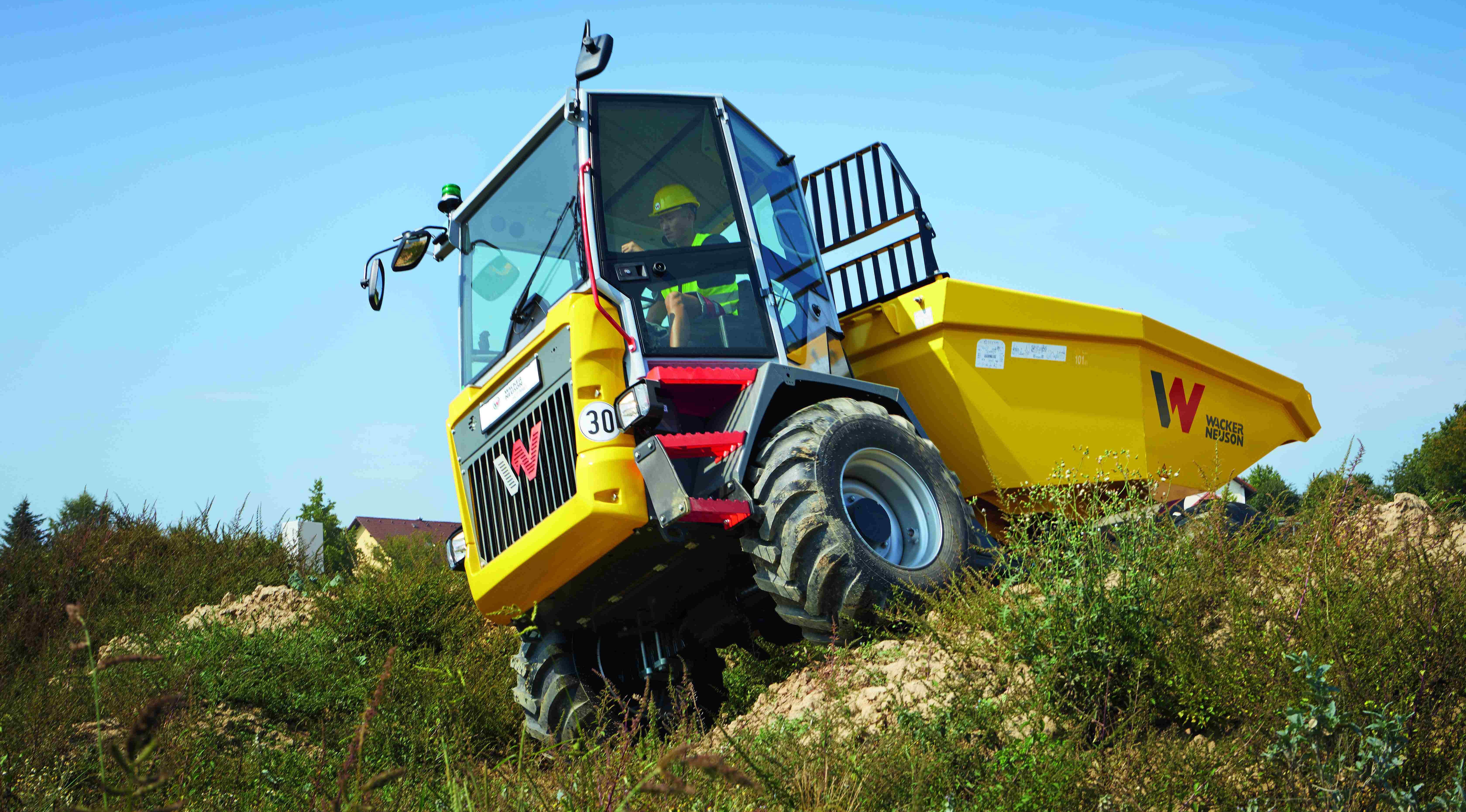 Dumper značky Wacker Neuson jedoucí po nerovném terénu s řidičem v kabině během stavebních prací