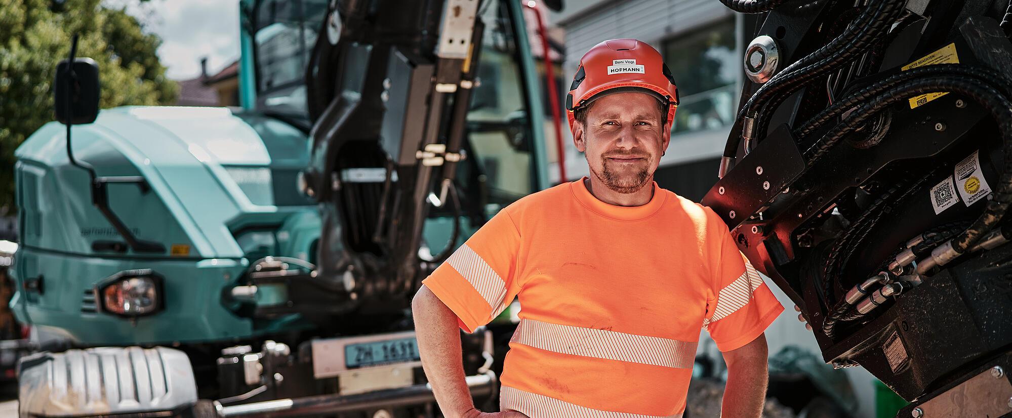 Stavební dělník stojící vedle kolového rypadla Wacker Neuson EW100 vybaveného hydraulickým nástavcem.