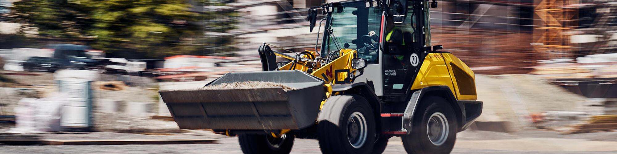 Výkonný kolový nakladač Wacker Neuson WL950p jede vysokou rychlostí na staveništi.