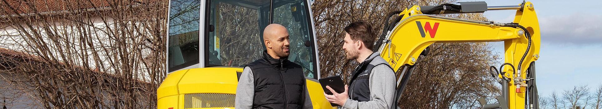 Zaměstnanec společnosti Wacker Neuson radí zákazníkovi o možnosti výměny použitých strojů před stroji Wacker Neuson.