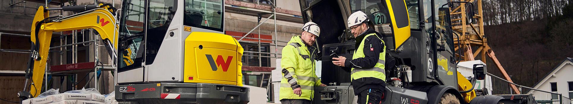 two customers standing in front of wacker neuson machines