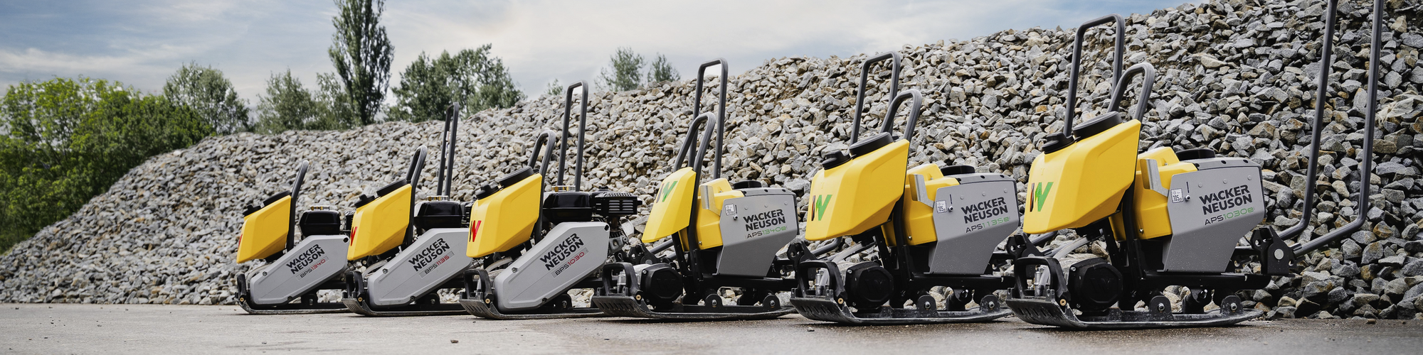 Vibrační desky Wacker Neuson APS a BPS vedle sebe před hromadou štěrku.