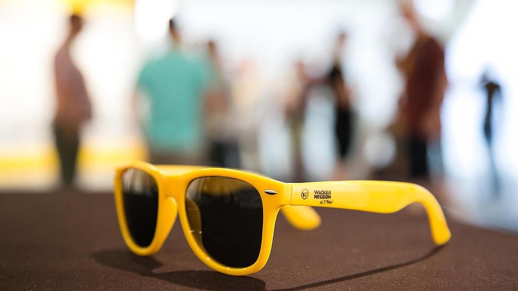 Žluté sluneční brýle s logem Wacker Neuson.