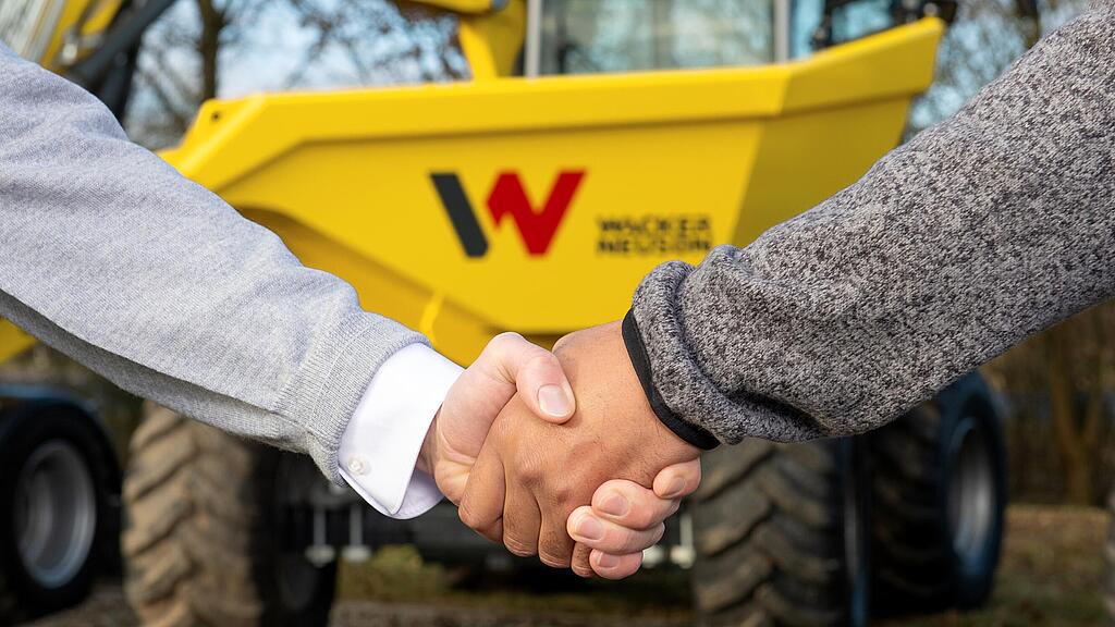 Podání ruky mezi konzultantkou Wacker Neuson a zákazníkem před dumperem Wacker Neuson.