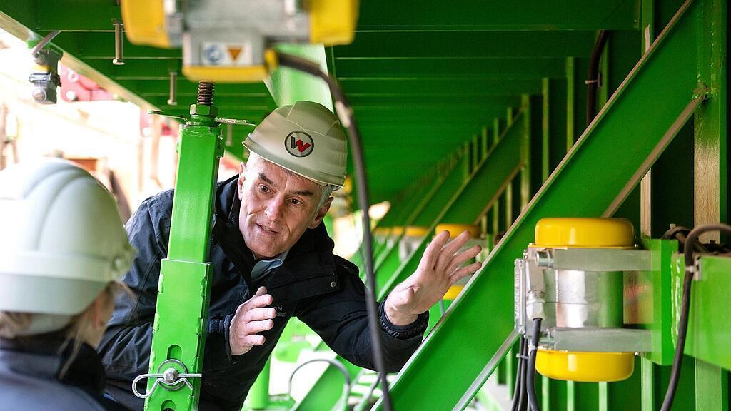 Zaměstnanec Wacker Neuson stojí před příložným vibrátorem a podává k němu výklad.