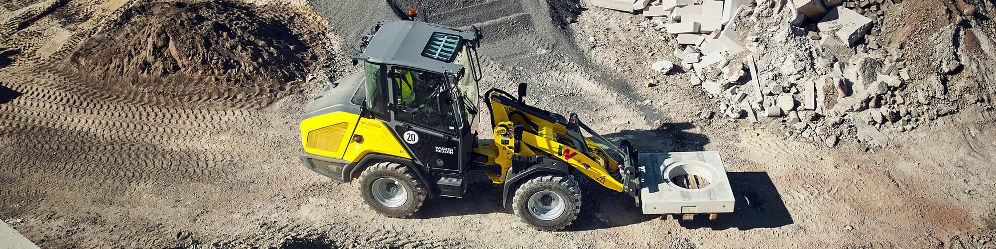 Výkonný kolový nakladač Wacker Neuson WL750p přepravuje betonový prvek na staveništi.
