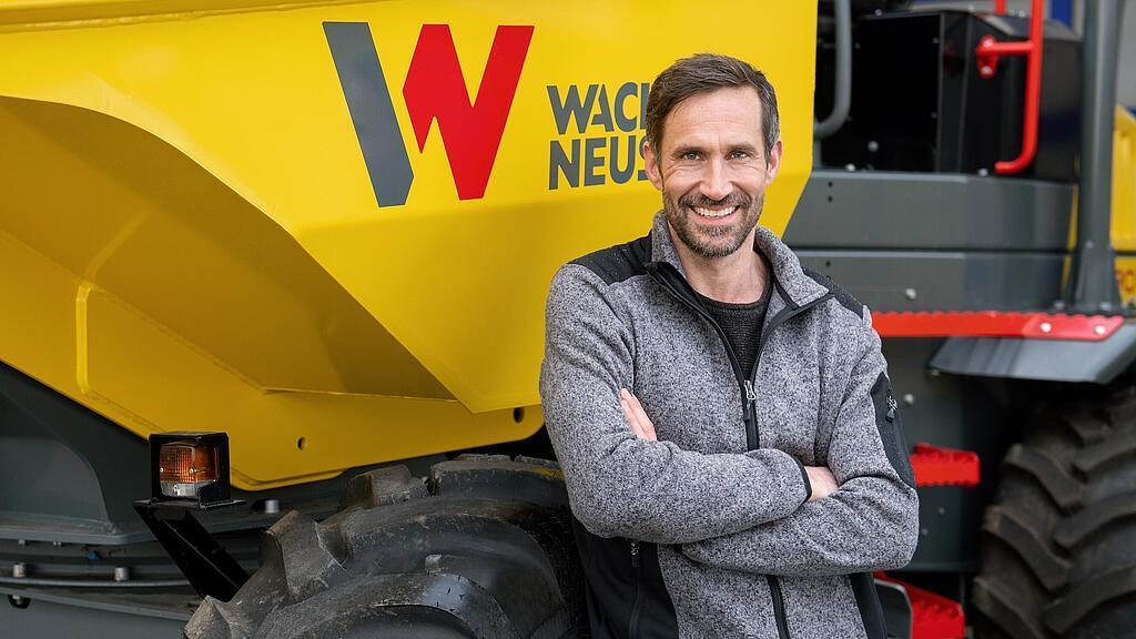 Wacker Neuson customer standing and smiling with arms folded in front of a Wacker Neuson wheel dumper.