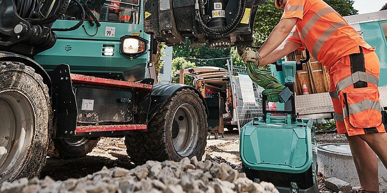 Obsluha vyměňuje přídavné zařízení na kolovém rypadle Wacker Neuson EW100 během prací na staveništi.